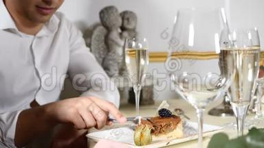 餐馆里的年轻人用叉子吃甜点。 桌上放着一杯香槟。 品尝草莓芝士蛋糕。 高清高清